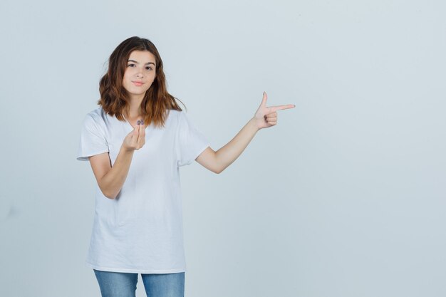 Portrait of young girl doing Italian gesture, pointing to the right side in white t-shirt, jeans and looking confident front view