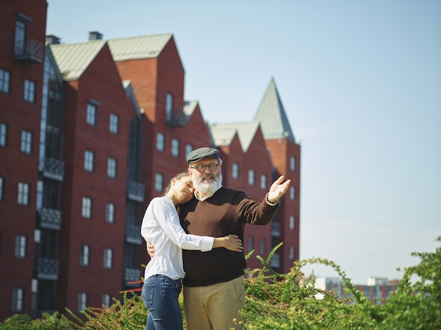 Free photo portrait of young girl embracing grandfather at park