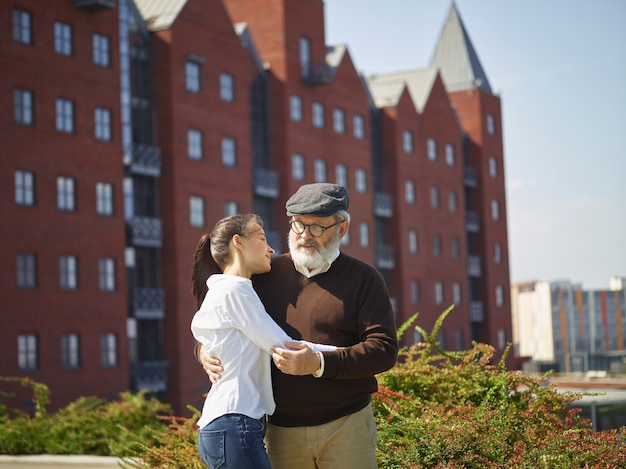 Free photo portrait of young girl embracing grandfather at park