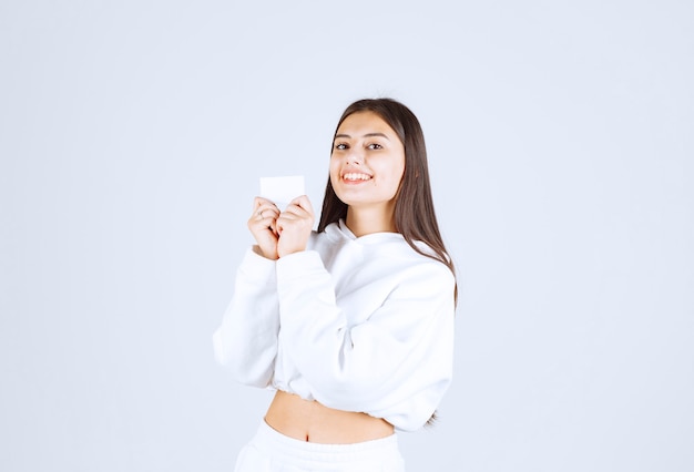 Portrait of a young girl model with a card on white-gray background.