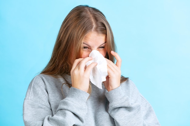 Free photo portrait of young girl sneezing isolated. cold and flu. winter sickness