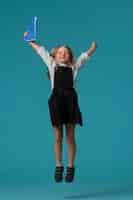 Free photo portrait of young girl student in school uniform jumping mid-air