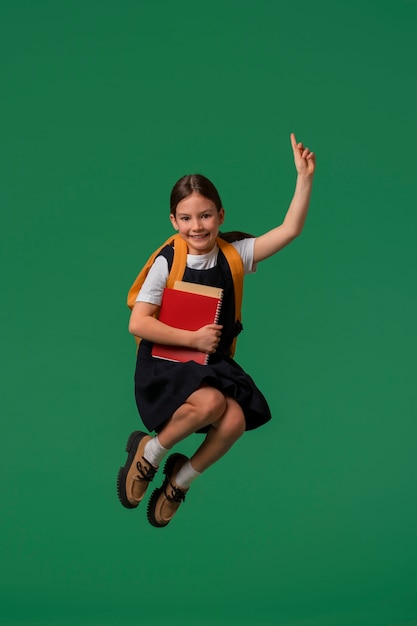 Portrait of young girl student in school uniform jumping mid-air