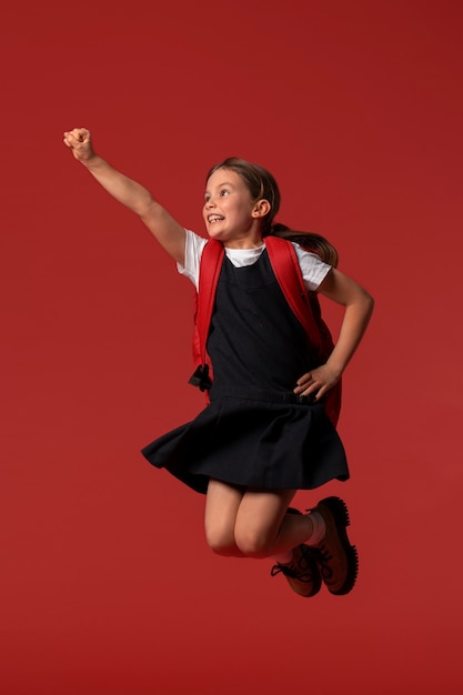 Free Photo portrait of young girl student in school uniform jumping mid-air