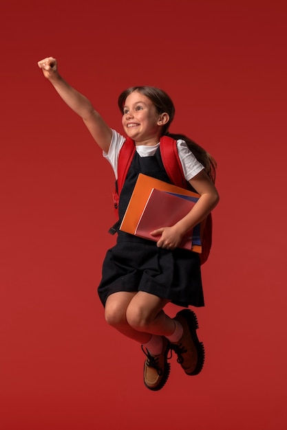 Free Photo portrait of young girl student in school uniform jumping mid-air