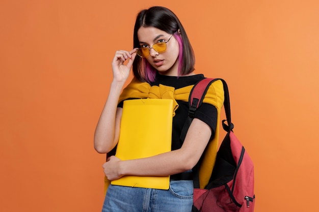 Free Photo portrait of a young girl wearing sunglasses and holding her folder