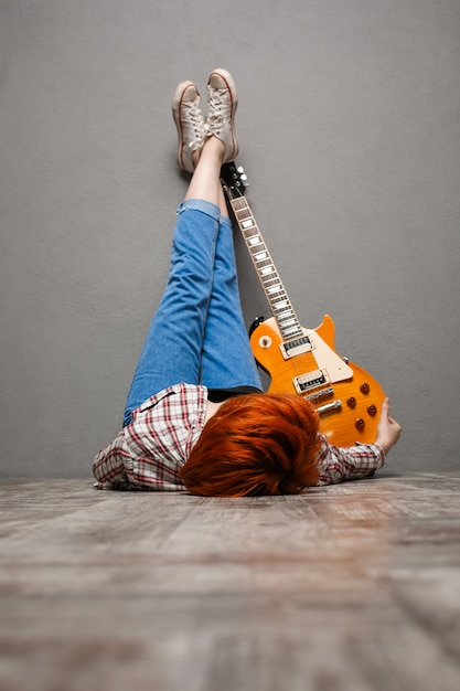 Free photo portrait of young girl with guitar over grey background.