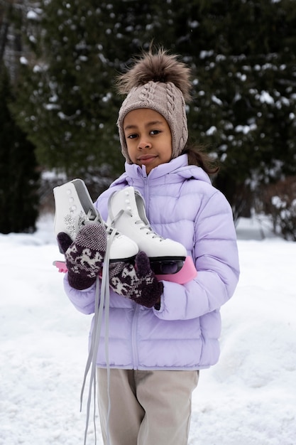 Free Photo portrait of young girl with ice skates outdoors in winter