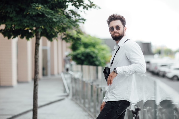 Free Photo portrait of a young handsome stylish guy in a white shirt on the streets of the city in sunglasses