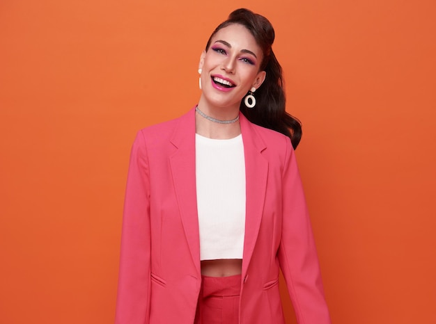 Portrait of young happy beautiful woman smiling and standing isolated on orange background