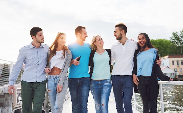 Portrait of a young and happy people at rest on the pier. Friends enjoying a game on the lake. Positive emotions.