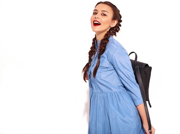 Free photo portrait of young happy smiling woman model with bright makeup and red lips with two pigtails in hands in summer colorful blue dress and backpack isolated