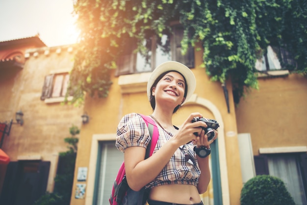 Portrait of young hipster woman backpack traveling taking photo in urban. 