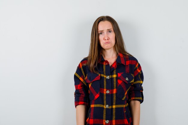 Portrait of young lady looking at camera in casual shirt and looking sad front view