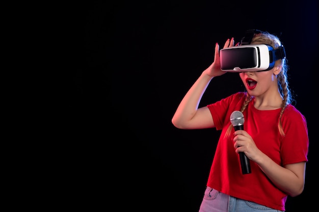 Portrait of young lady playing vr and singing on dark wall