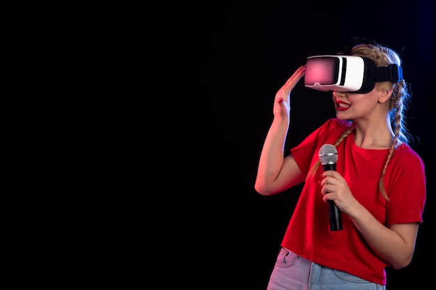 Portrait of young lady playing vr and singing on dark wall