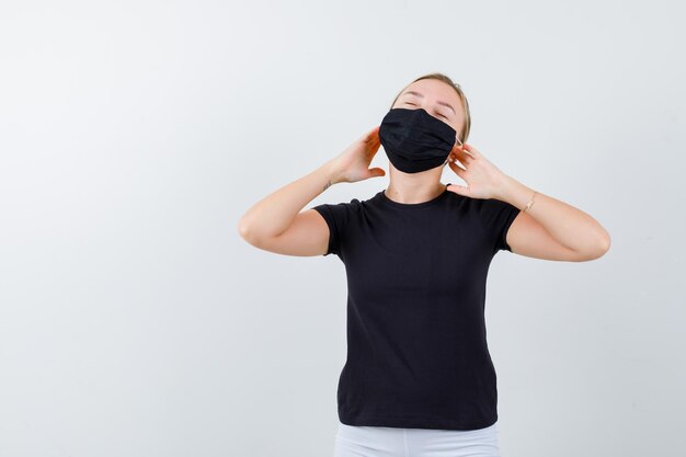 Portrait of young lady plugging ears with fingers in t-shirt, pants