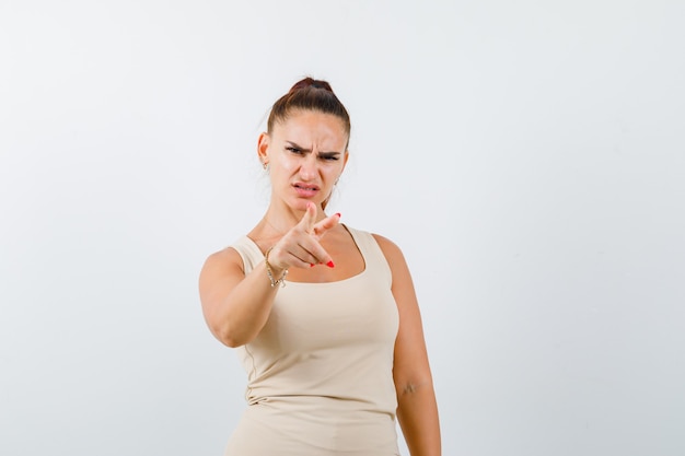 Free Photo portrait of young lady pointing at camera in tank top and looking angry front view