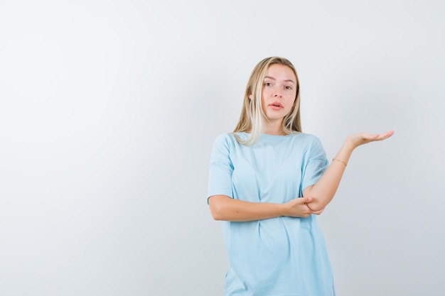 Portrait of young lady showing something in t-shirt and looking confident isolated