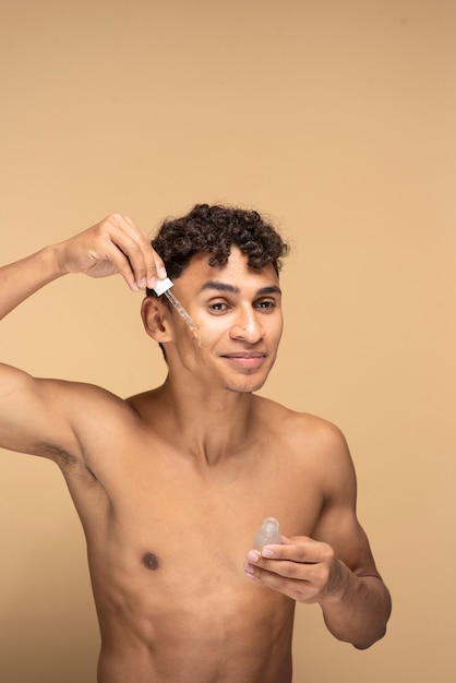 Portrait of a young man applying serum on his face