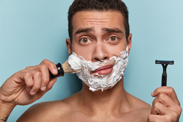 Free photo portrait of young man applying shaving foam