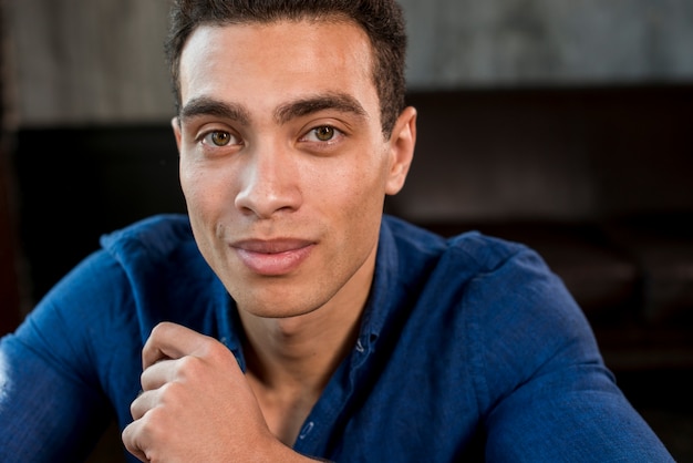 Free photo portrait of a young man in blue shirt looking at camera