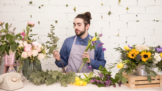 Free photo portrait of a young man creating the flower bouquet in the flower shop