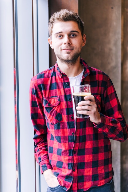 Free Photo portrait of a young man holding beer glass looking at camera