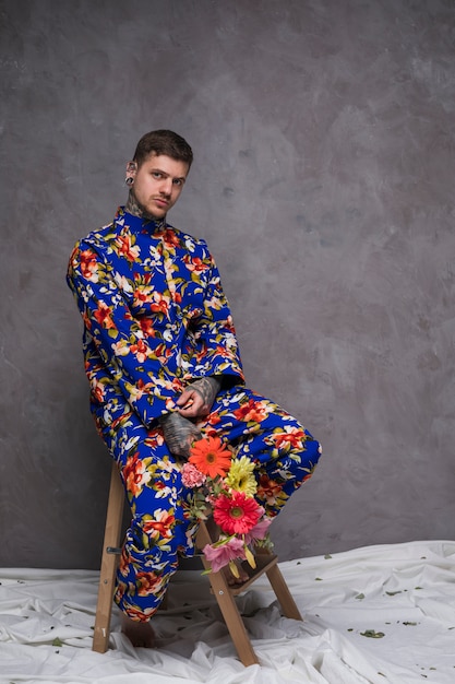 Portrait of a young man holding flower in hands looking at camera