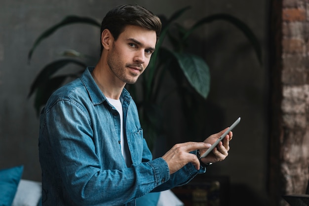 Free Photo portrait of young man looking holding digital tablet in hand looking at camera