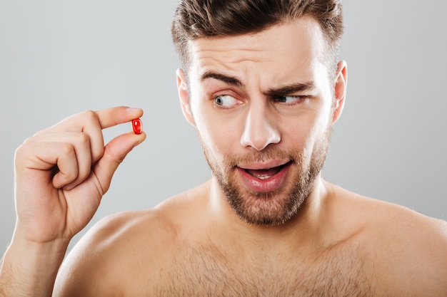 Portrait of a young man looking at red capsule