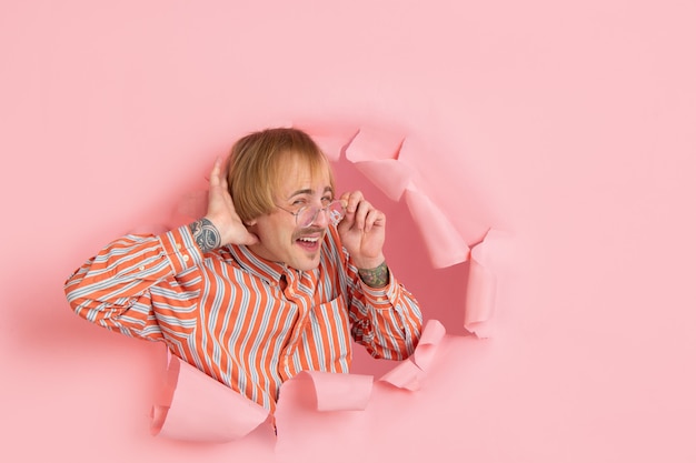 Free Photo portrait of young man on pink torn breakthrought background