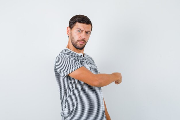 Free Photo portrait of young man pointing back in t-shirt and looking hesitative front view