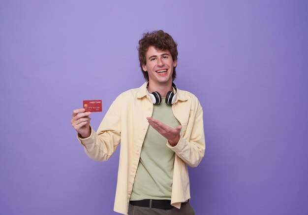 Portrait young man presenting credit card in hand showing trust and confidence for making payment