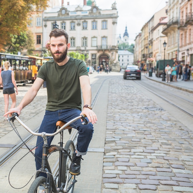 Free photo portrait of a young man riding bicycle in city