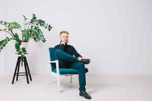 Free photo portrait of a young man sitting on chair in an office