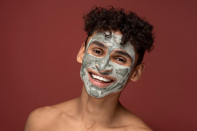 Portrait of a young man smiling with a beauty face mask on