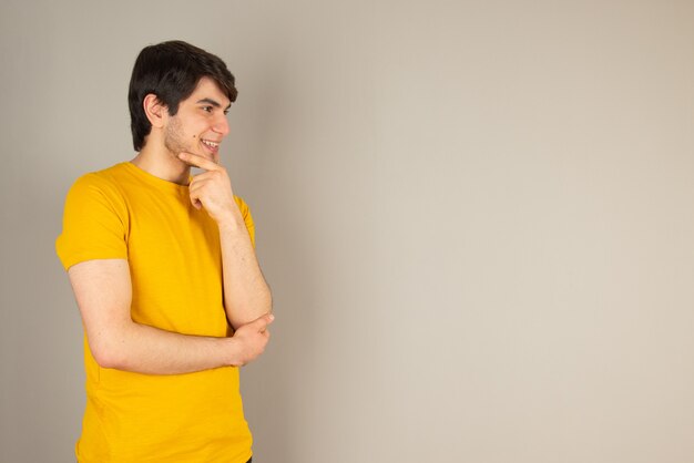 Portrait of a young man standing and looking away against gray.