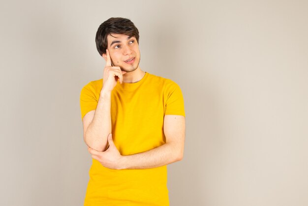 Portrait of a young man standing and posing against gray.