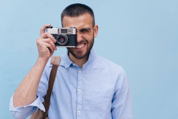 Portrait of young man taking picture with retro camera