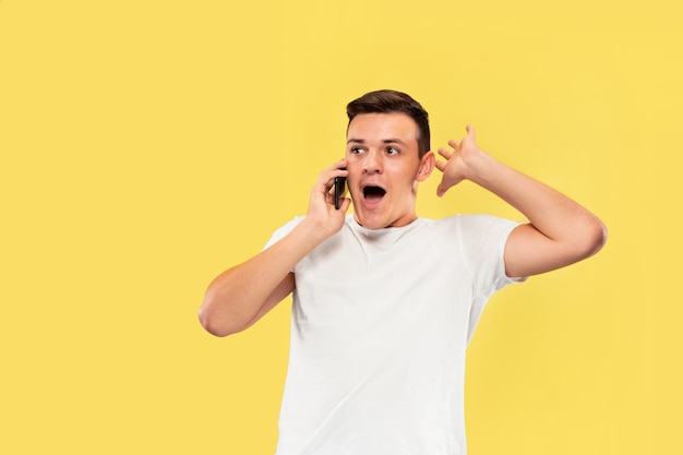 Portrait of young man talking on the phone isolated on yellow wall