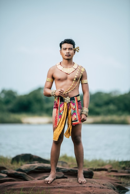 Portrait of Young man in traditional costume posing in nature in Thailand