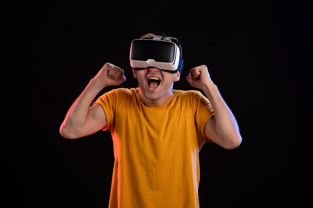 Portrait of young man wearing vr headset on dark wall