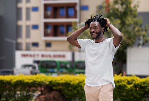 Free photo portrait of young man with afro dreadlocks and white t-shirt outdoors