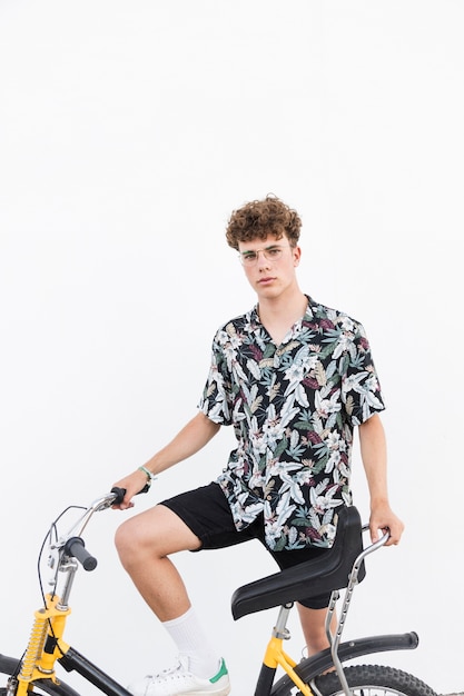 Free photo portrait of a young man with bicycle on white background