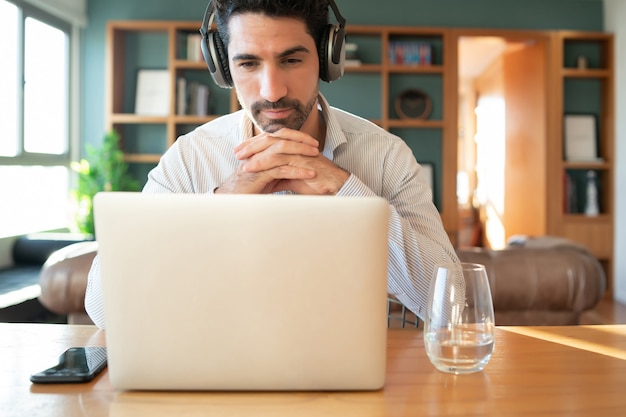 Portrait of young man on a work video call with laptop from home. Home office concept. New normal lifestyle.