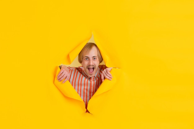 Portrait of young man on yellow torn breakthrought background