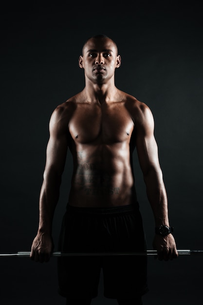 Portrait of young muscular afro american man holding barbell