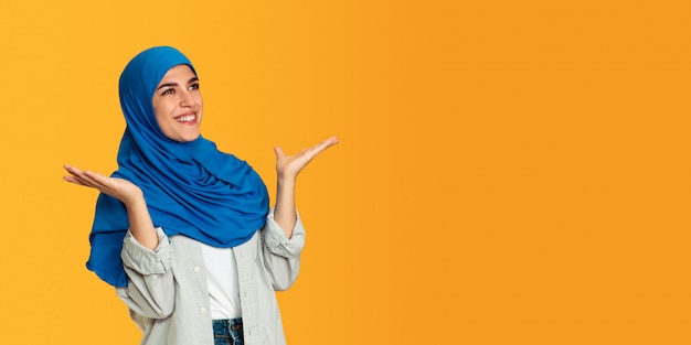 Portrait of young muslim woman isolated on yellow studio background