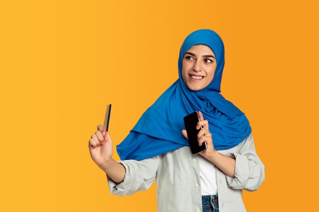 Portrait of young muslim woman isolated on yellow studio background